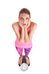 Photo of Sad young woman measuring her weight using scales on white background. Weight loss motivation