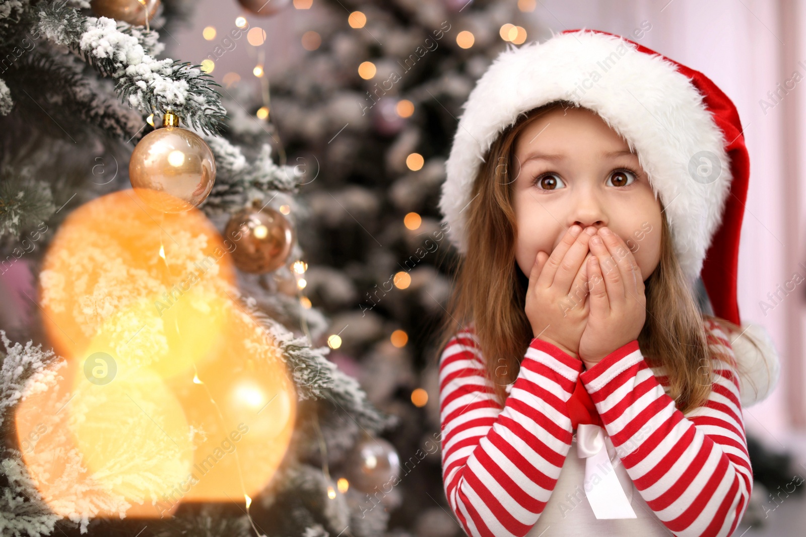 Photo of Surprised child near Christmas tree at home. Space for text