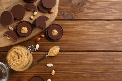 Photo of Flat lay composition with delicious peanut butter cups on wooden table, space for text