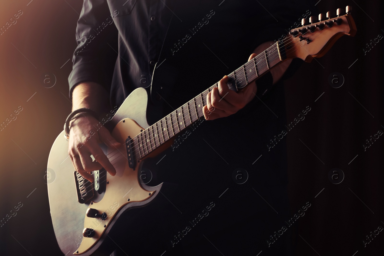 Photo of Man playing electric guitar on stage, closeup. Rock music