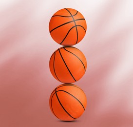 Image of Stack of basketball balls on coral background