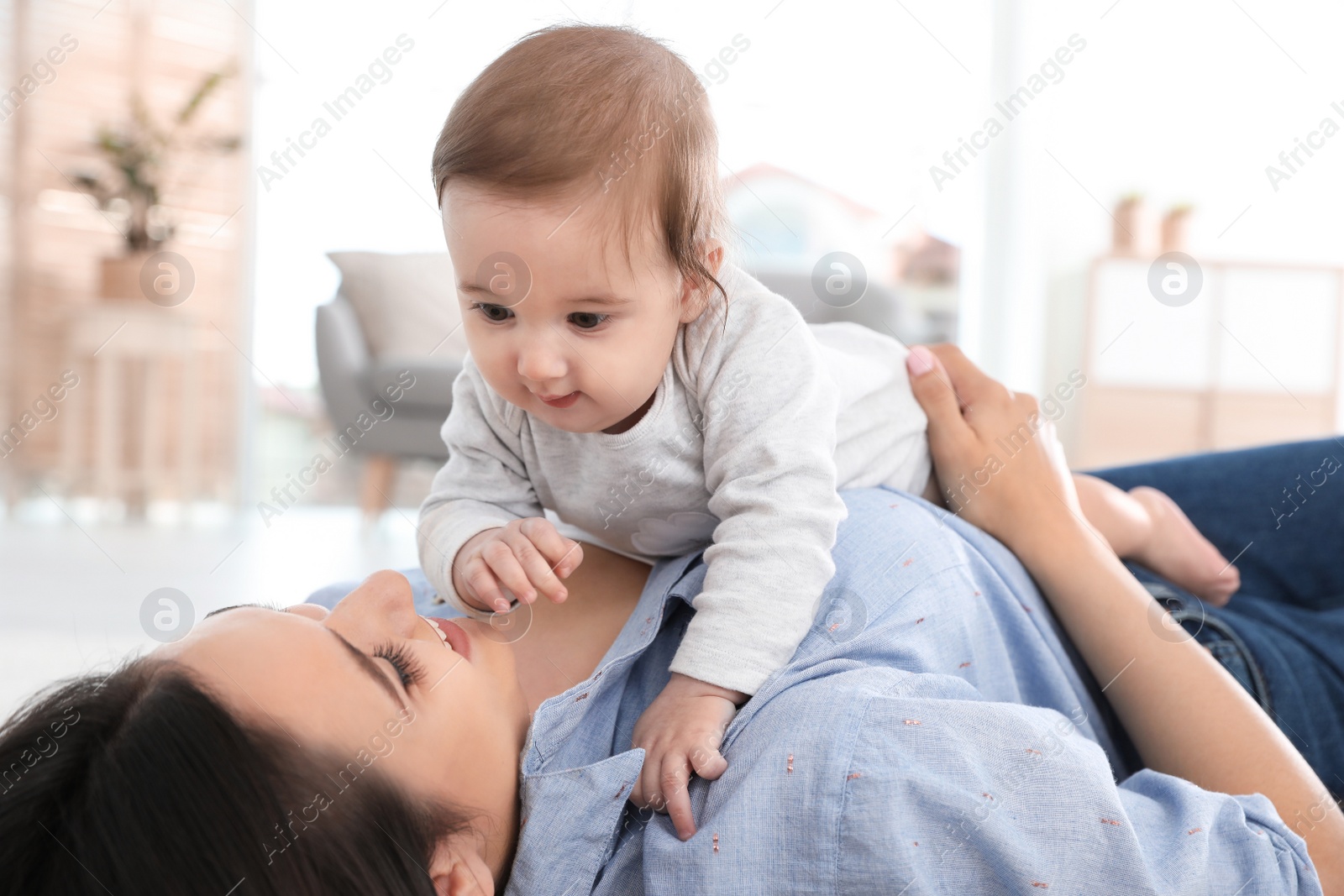 Photo of Happy young mother playing with baby on floor at home