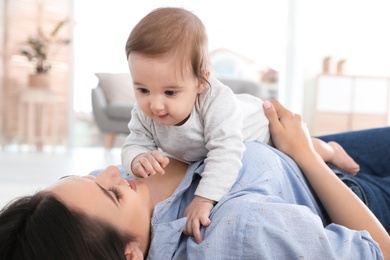 Happy young mother playing with baby on floor at home