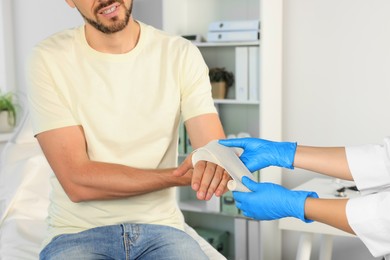 Photo of Doctor applying medical bandage onto patient's hand in hospital, closeup