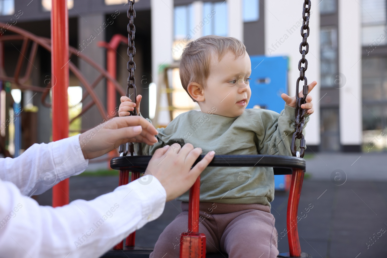 Photo of Nanny and cute little boy on swing outdoors