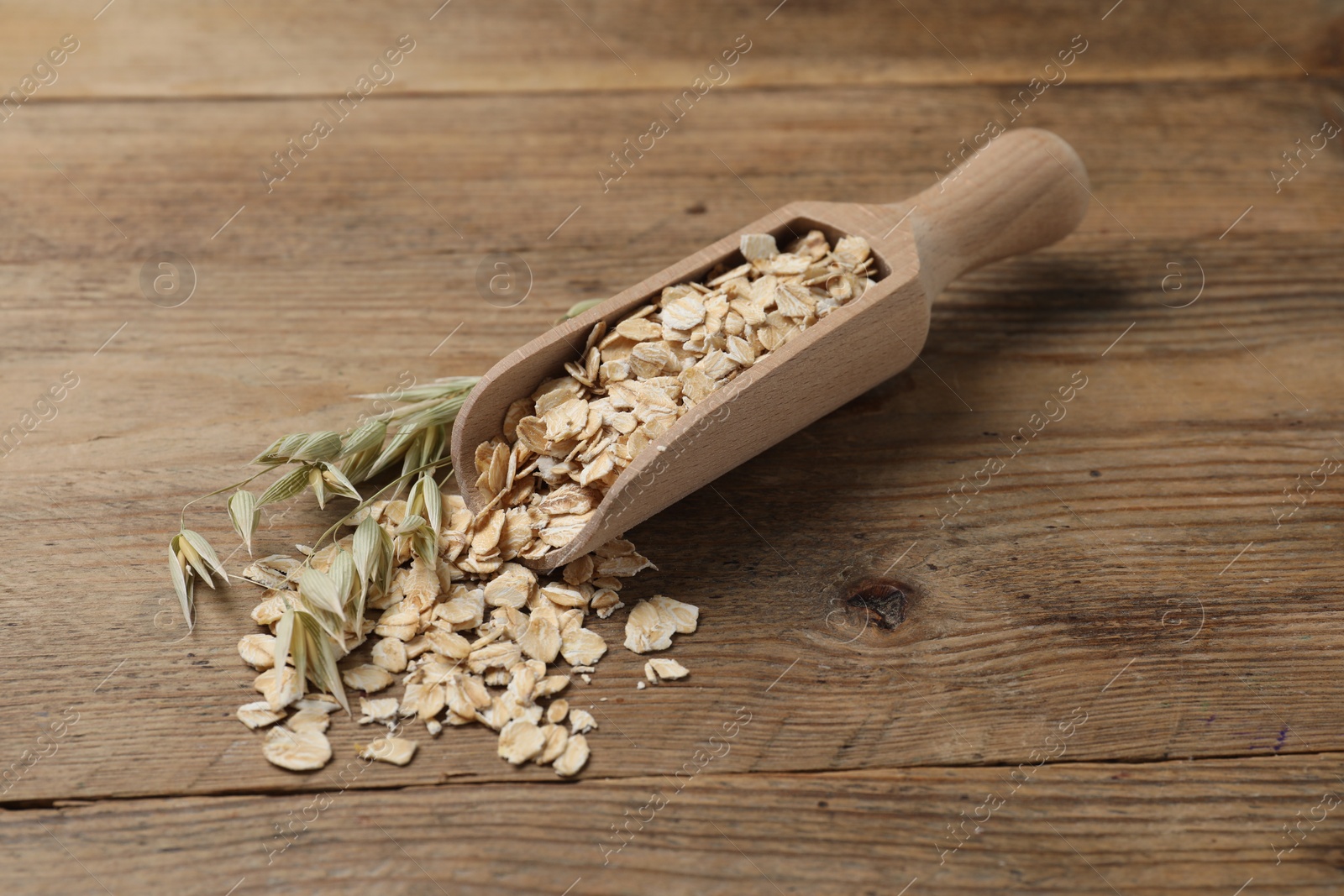 Photo of Scoop with oatmeal and floret branches on wooden table