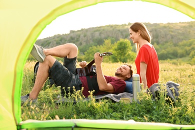 Photo of Young couple spending time together in wilderness, view from inside of camping tent