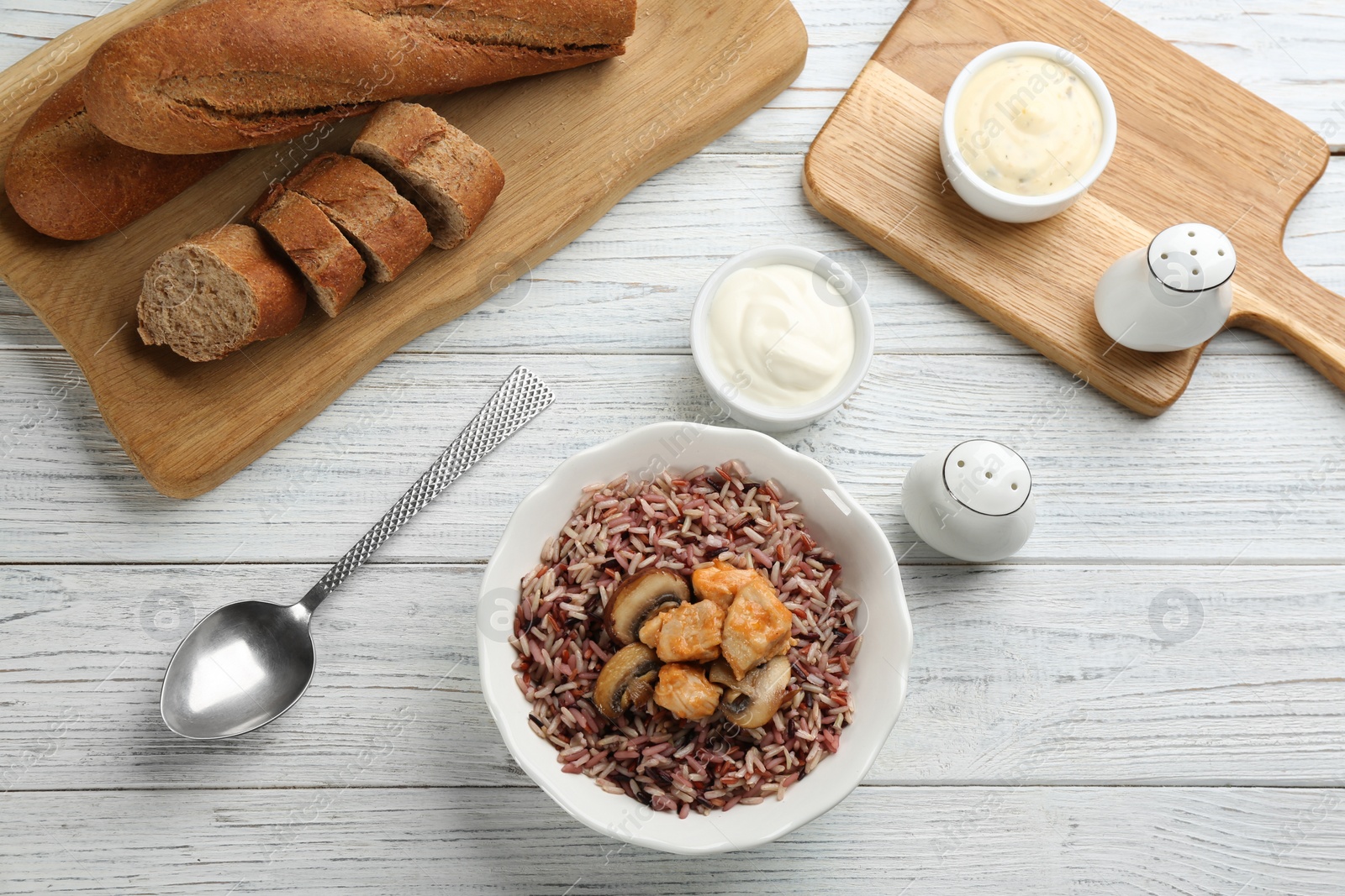 Photo of Delicious brown rice served on white wooden table, flat lay