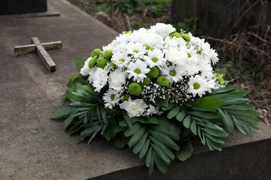 Photo of Funeral wreath of flowers on tombstone outdoors