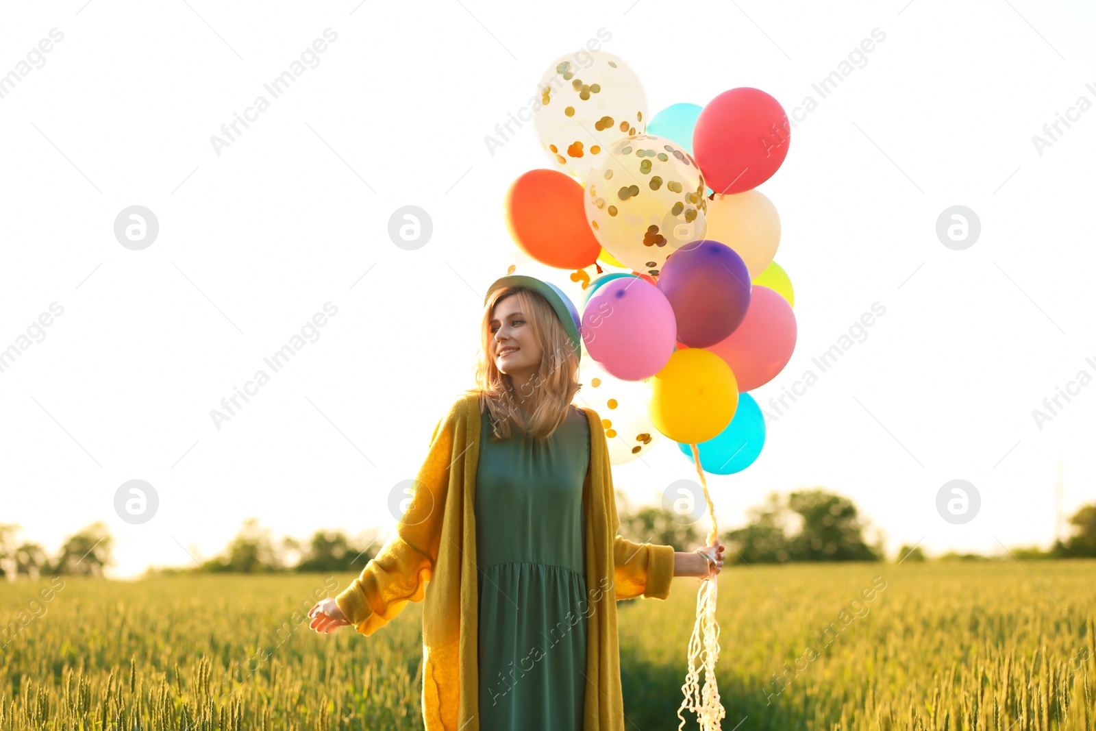 Photo of Young woman with colorful balloons in field on sunny day