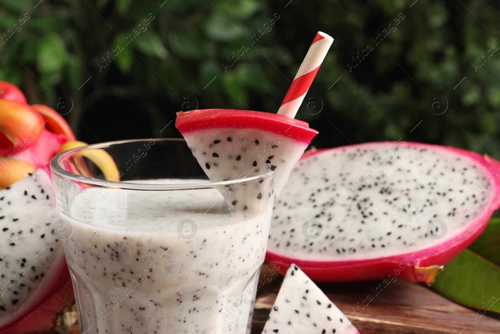 Photo of Delicious pitahaya smoothie and fresh fruits on blurred background, closeup