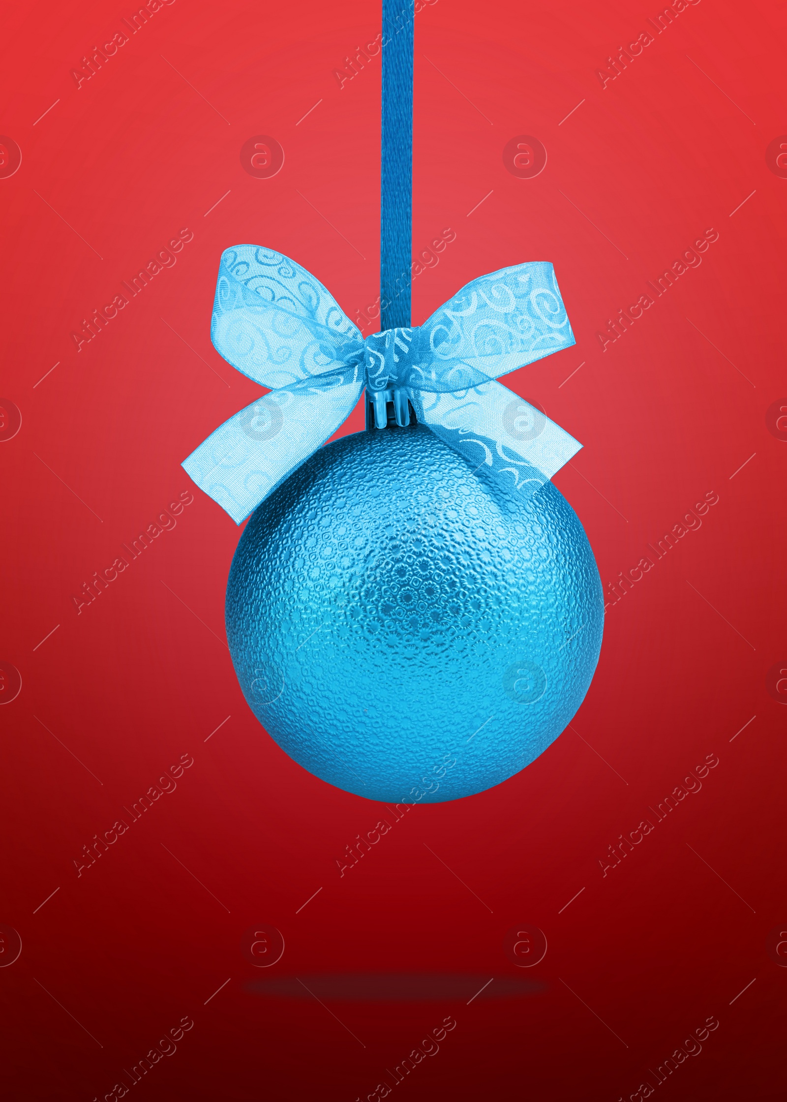 Image of Beautiful blue Christmas ball with bow hanging on red background