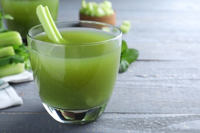 Photo of Glass of fresh celery juice on grey wooden table, closeup