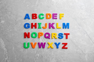 Colorful magnetic letters on light grey marble background, flat lay. Alphabetical order
