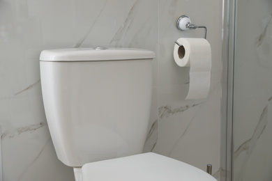 Photo of Modern toilet and holder with paper roll indoors