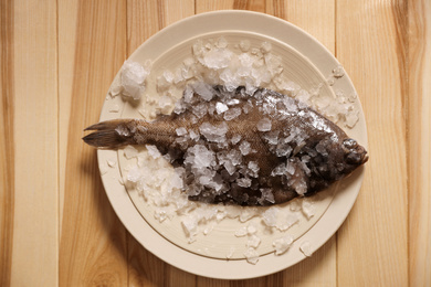 Fresh raw fish with ice on wooden table, top view