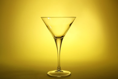 Photo of Elegant empty martini glass on yellow background