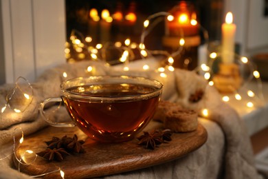 Glass cup of aromatic anise tea on wooden board indoors, bokeh effect