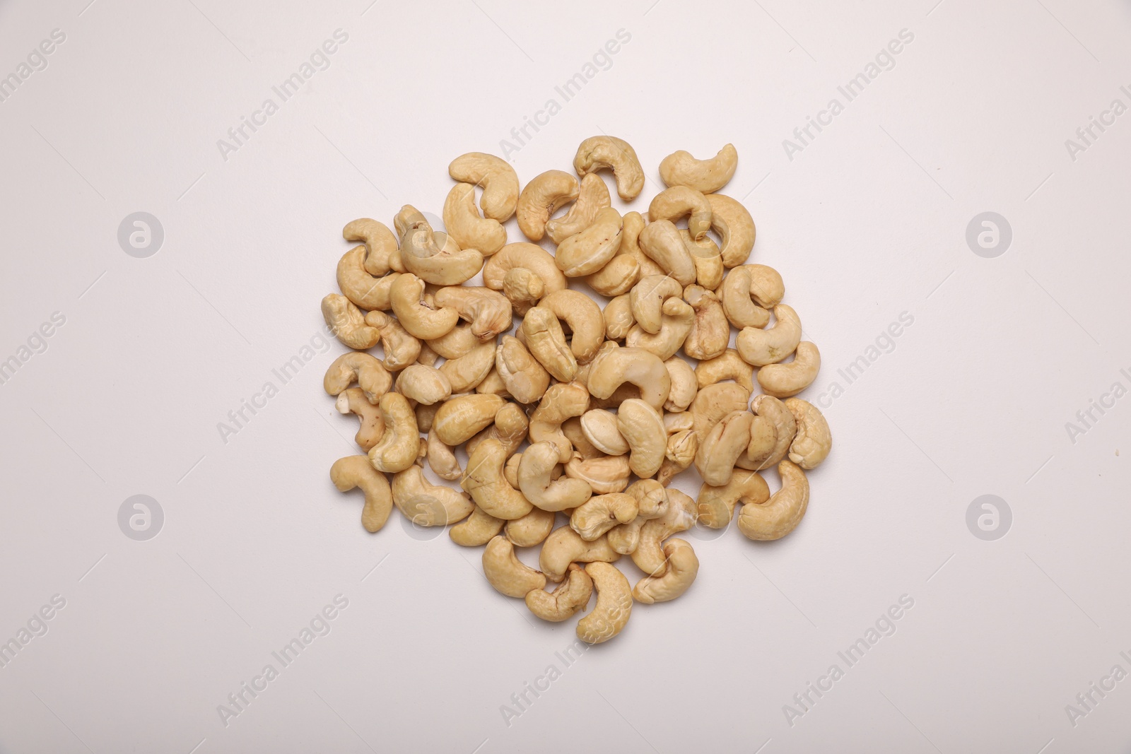 Photo of Pile of tasty cashew nuts on white background, top view