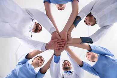 Photo of Teammedical doctors putting hands together indoors, bottom view