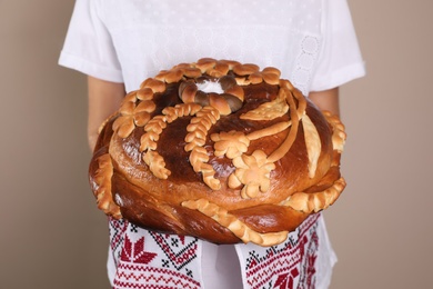 Photo of Woman with korovai on grey background, closeup. Ukrainian bread and salt welcoming tradition