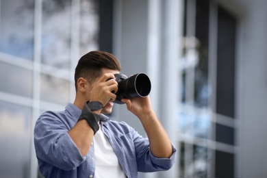 Photographer taking picture with professional camera on city street