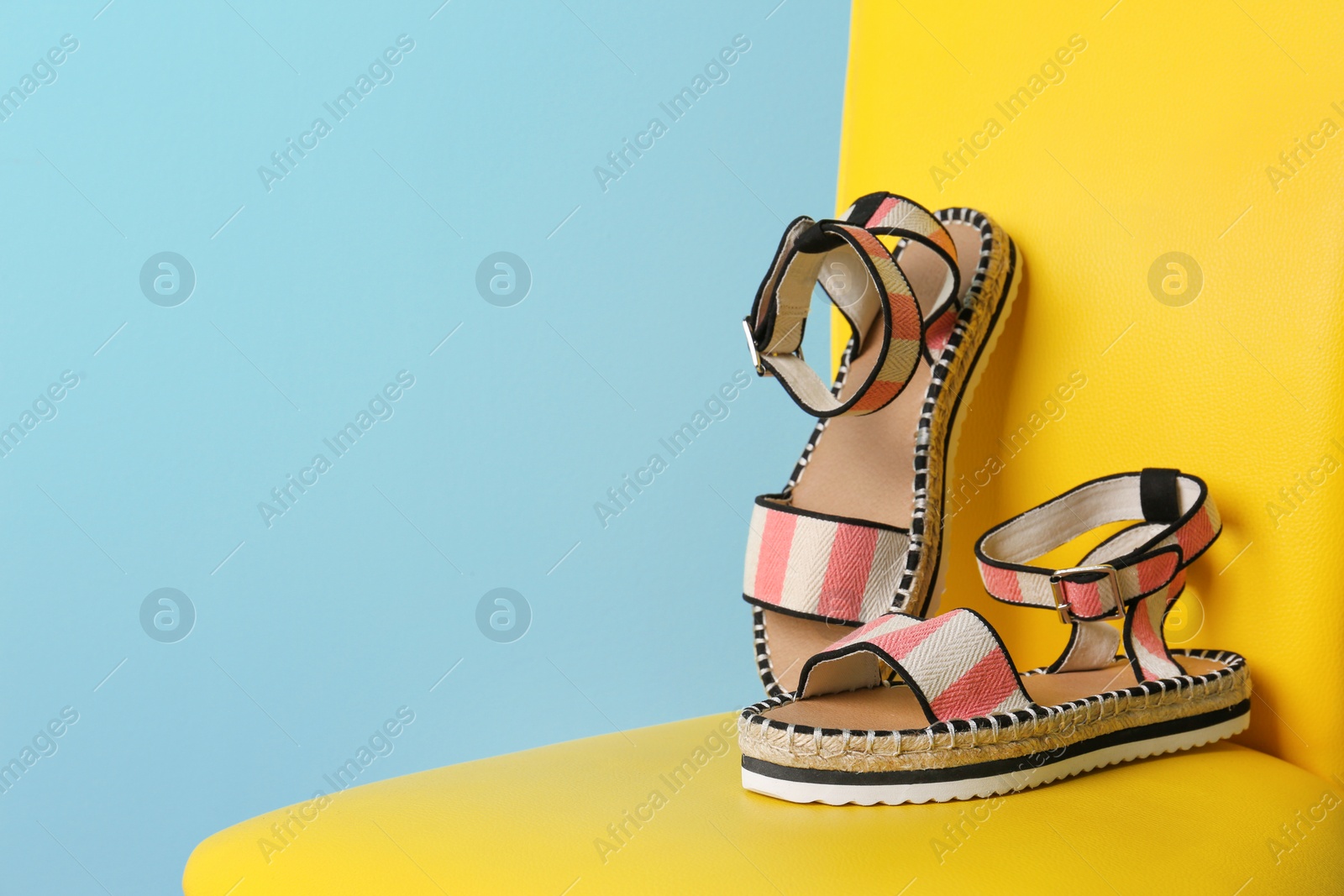 Photo of Pair of female shoes on chair against color background