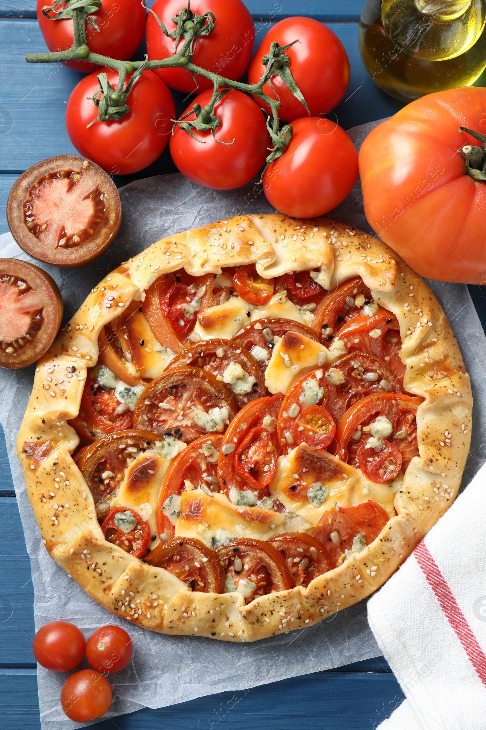 Photo of Flat lay composition of tasty galette with tomato and cheese (Caprese galette) on blue wooden table