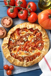 Flat lay composition of tasty galette with tomato and cheese (Caprese galette) on blue wooden table