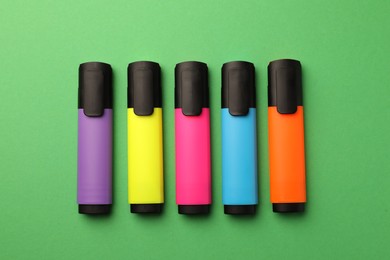 Bright color markers on green background, flat lay