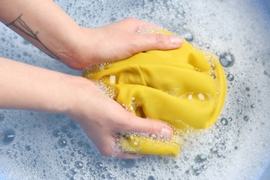 Photo of Top view of woman hand washing color clothing in suds, closeup