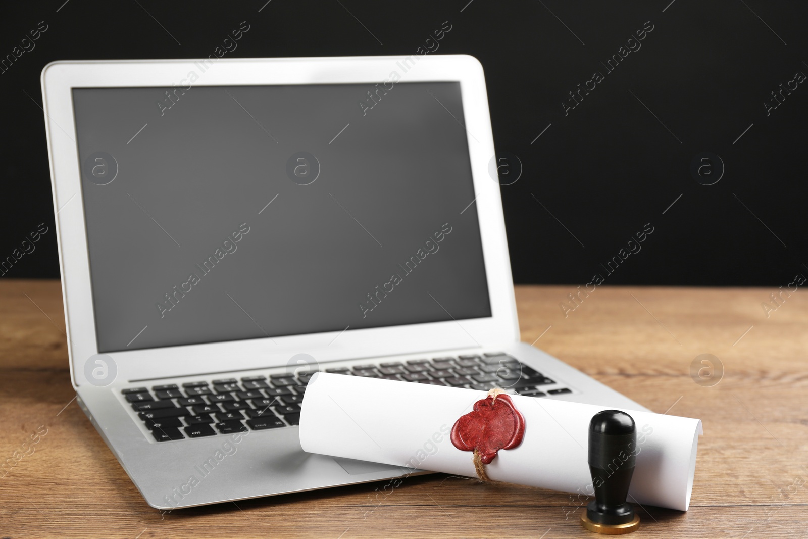 Photo of Notary's public pen and sealed document near laptop on wooden table