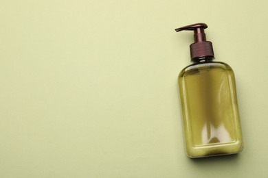 Photo of Bottle of shampoo on light green background, top view. Space for text