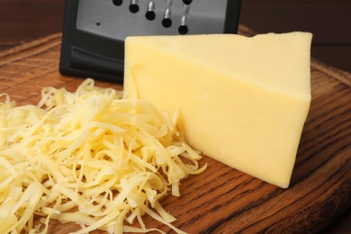 Photo of Grated and whole piece of cheese on wooden board, closeup