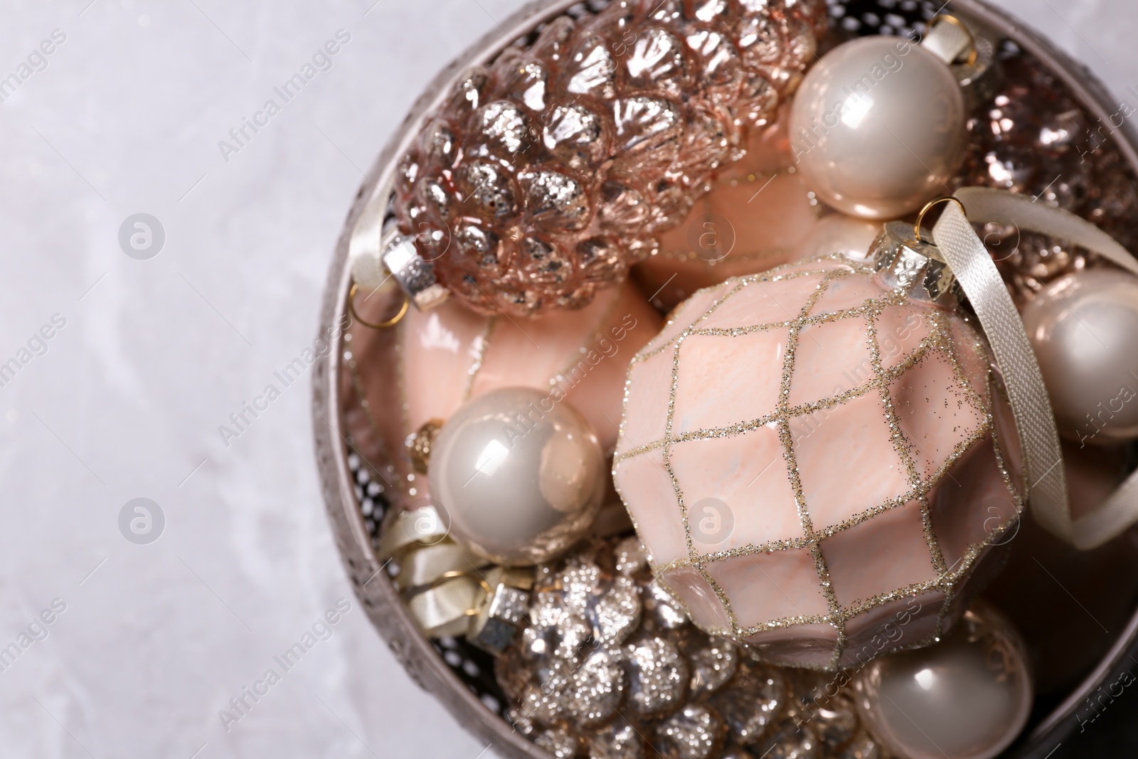 Photo of Christmas baubles in bowl on light grey table, top view