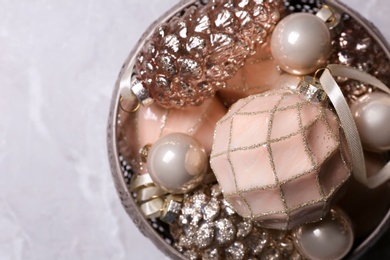 Photo of Christmas baubles in bowl on light grey table, top view