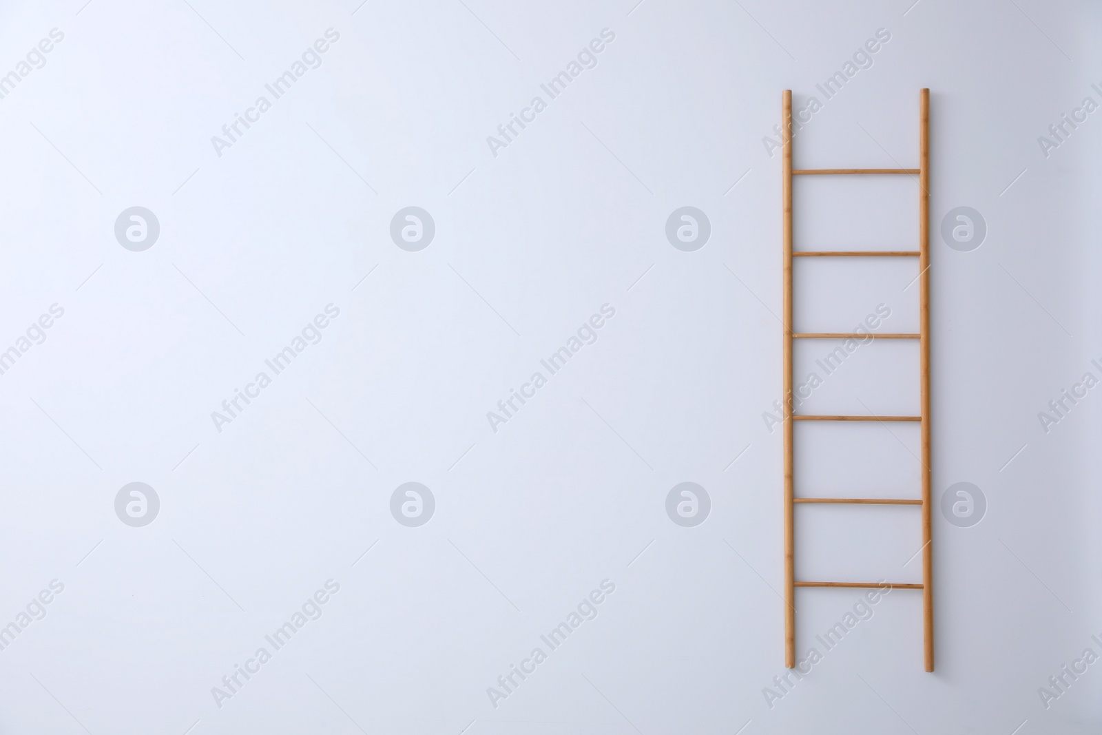 Photo of Modern wooden ladder on white background. Space for text