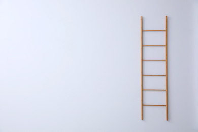 Photo of Modern wooden ladder on white background. Space for text