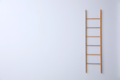 Modern wooden ladder on white background. Space for text