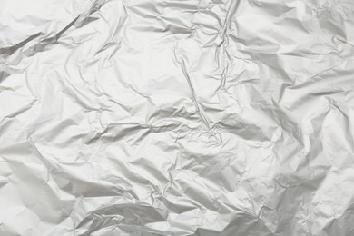 Crumpled silver foil as background, top view