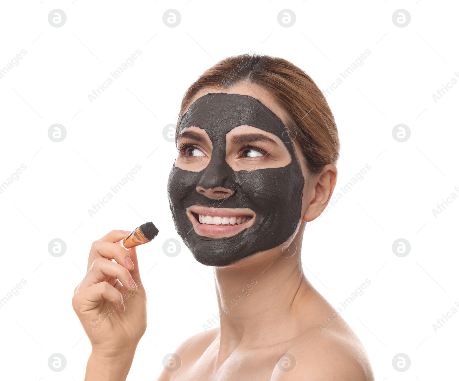 Photo of Beautiful woman applying black mask onto face against white background