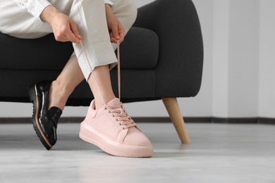 Photo of Woman taking off uncomfortable shoes and putting on sneakers in office, closeup