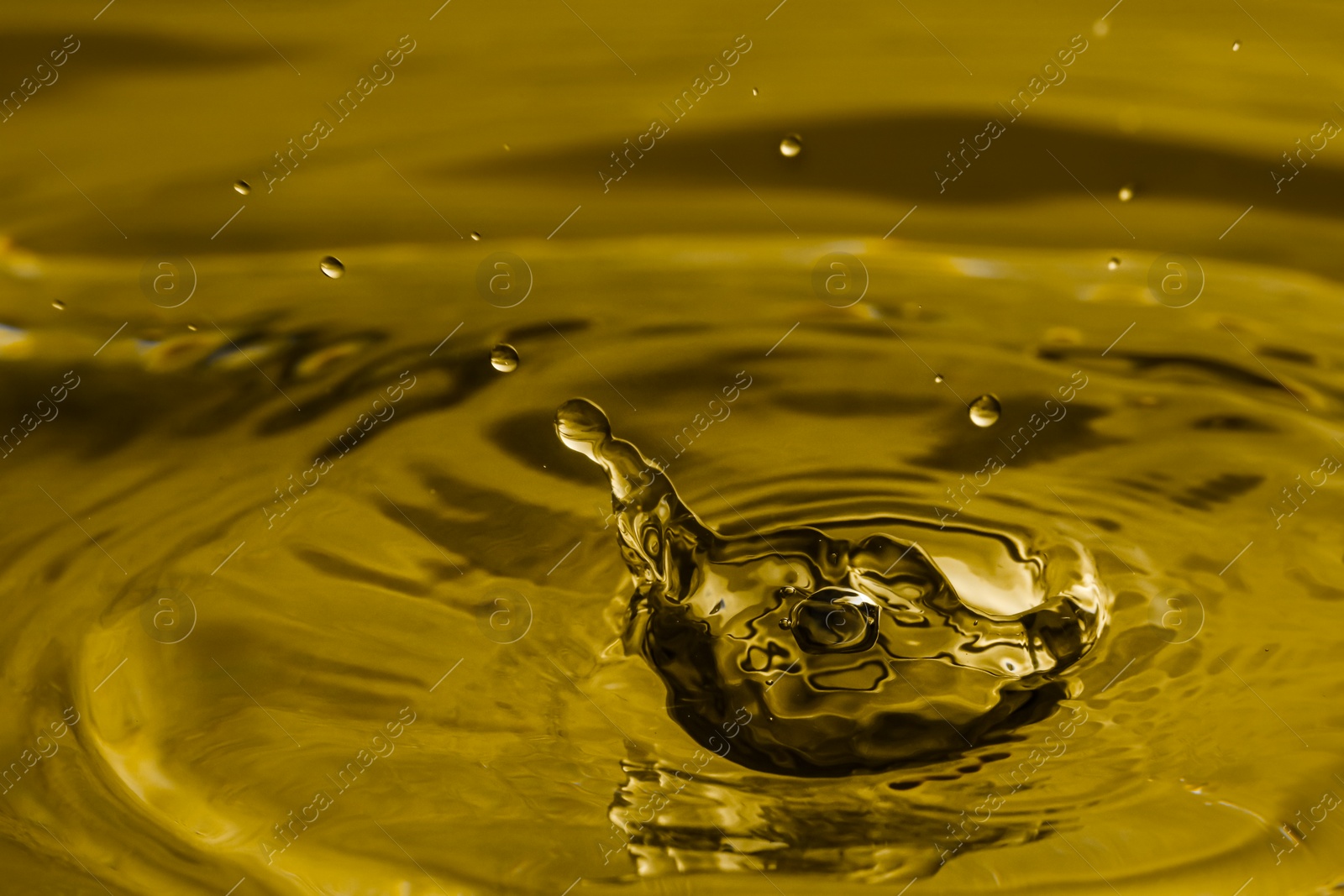 Image of Splash of golden oily liquid with drops as background, closeup