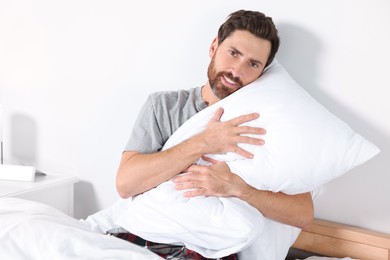 Man hugging pillow on bed at home