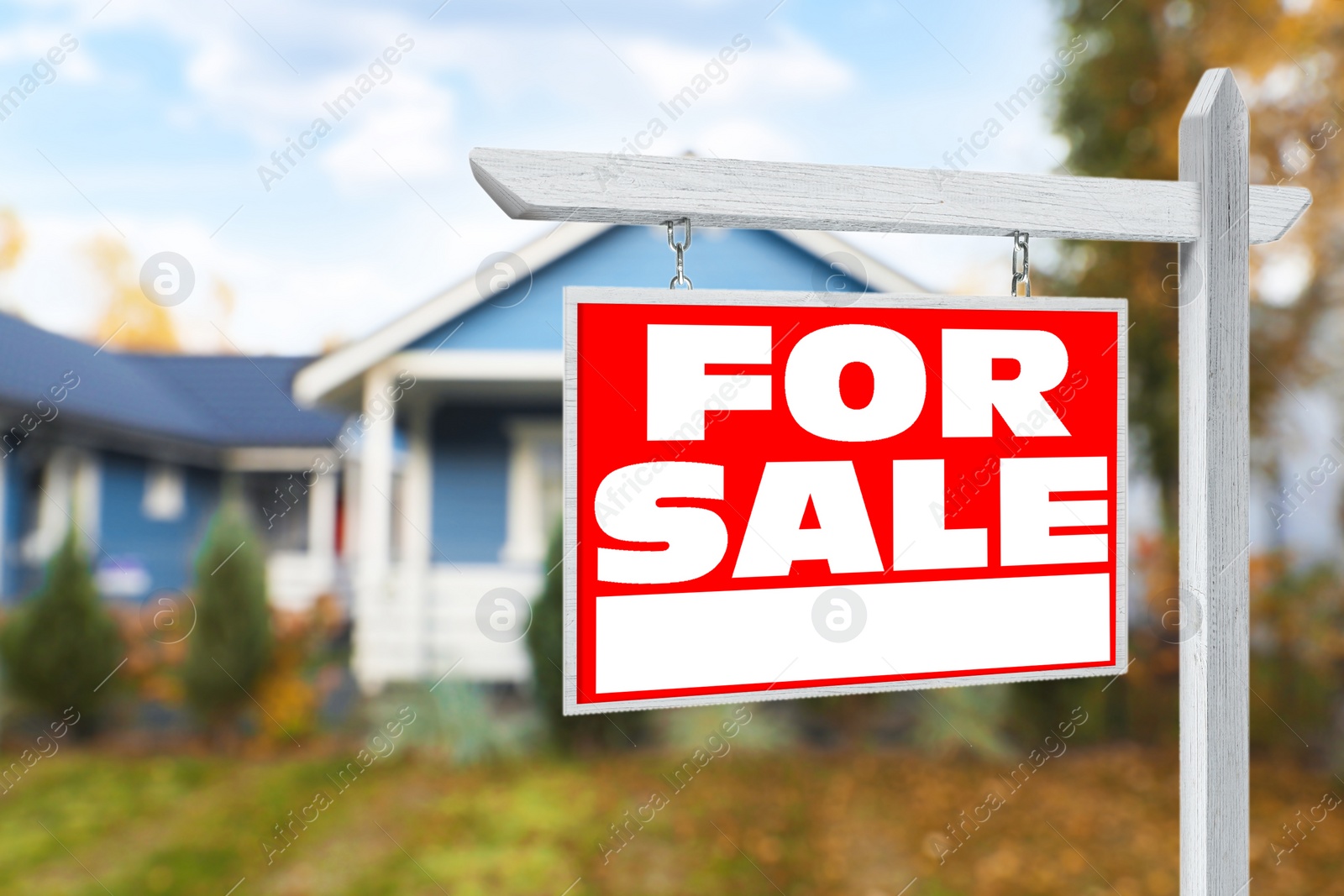 Image of Sale sign near beautiful house outdoors. Red signboard with words