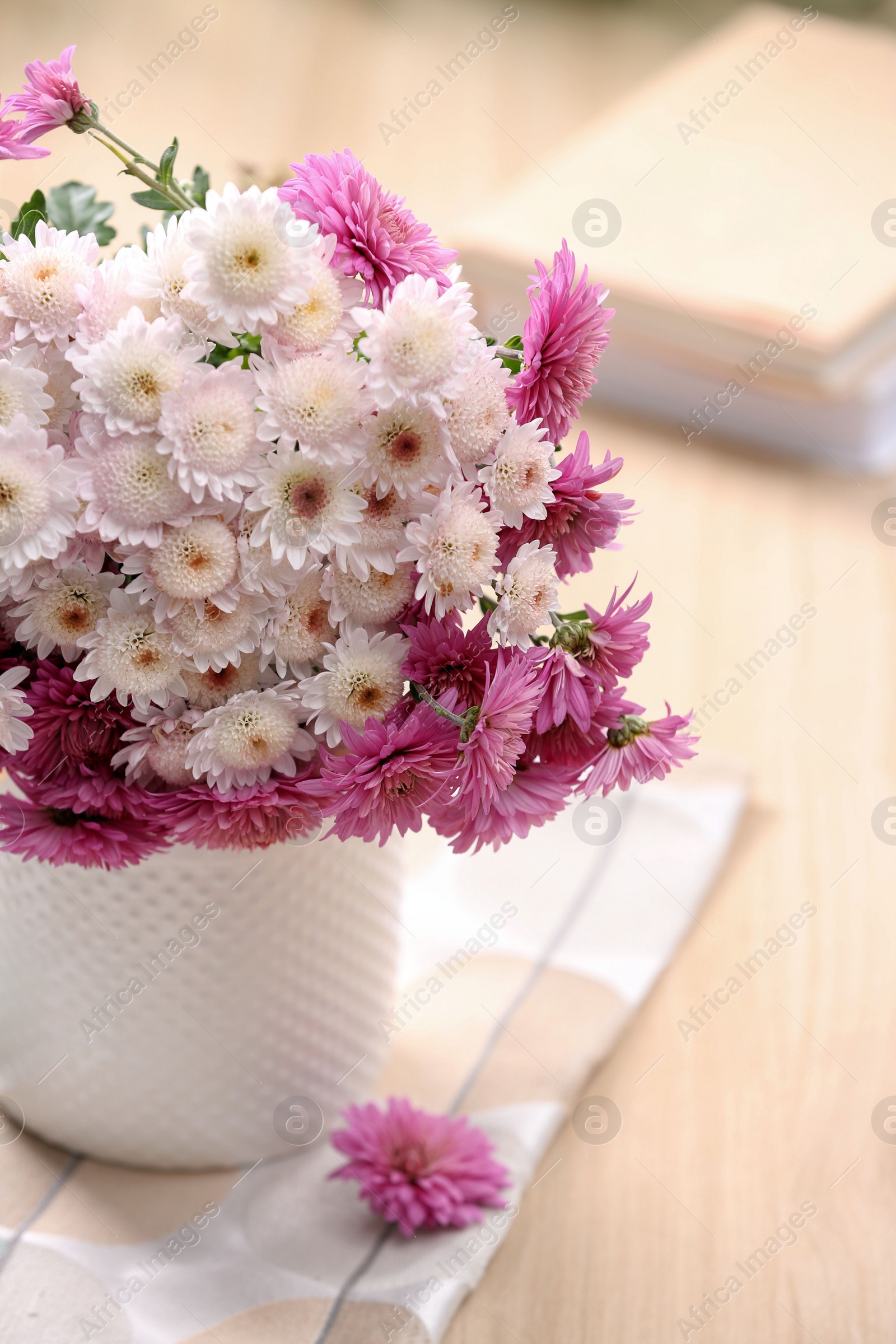 Photo of Vase with beautiful bouquet, books and cloth on wooden table