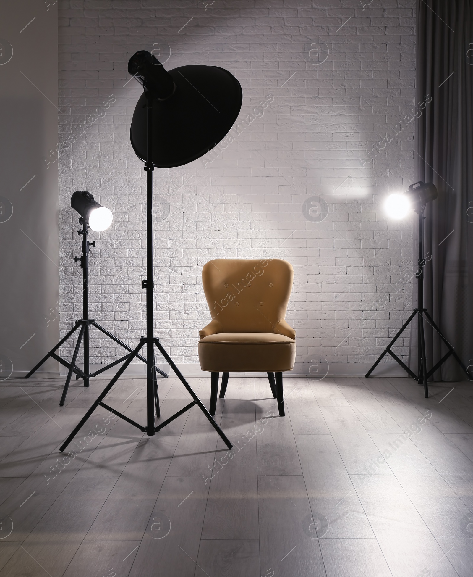 Photo of Interior of modern photo studio with professional lighting equipment and armchair