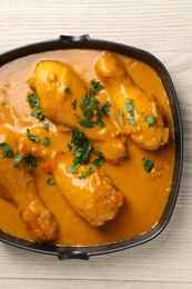 Photo of Tasty chicken curry with parsley on wooden table, top view