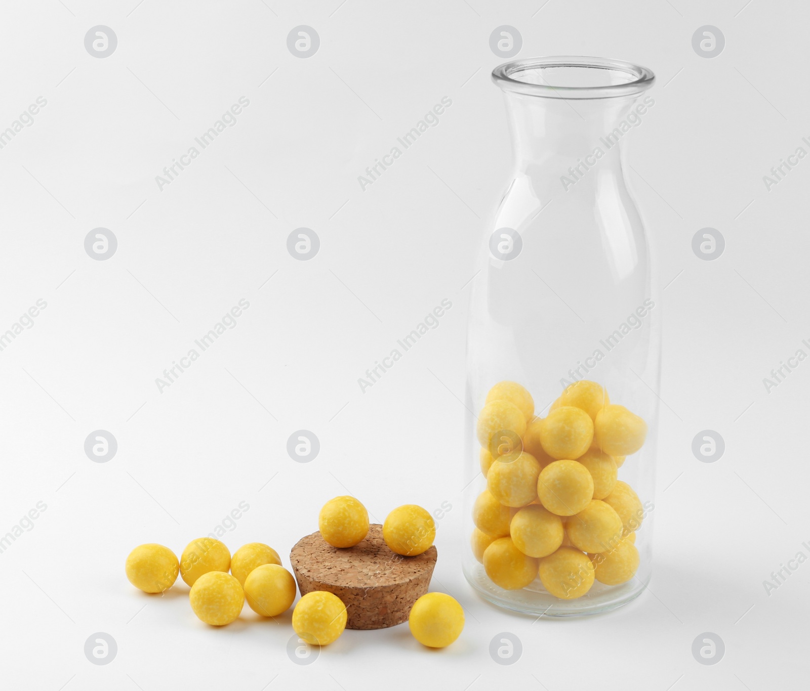 Photo of Tasty lemon drops and bottle on white background