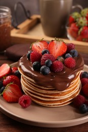 Stack of tasty pancakes with fresh berries and chocolate spread on table, closeup